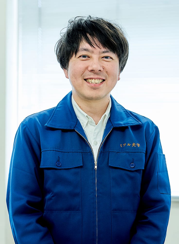 青い作業服を着て微笑む男性の採用担当者