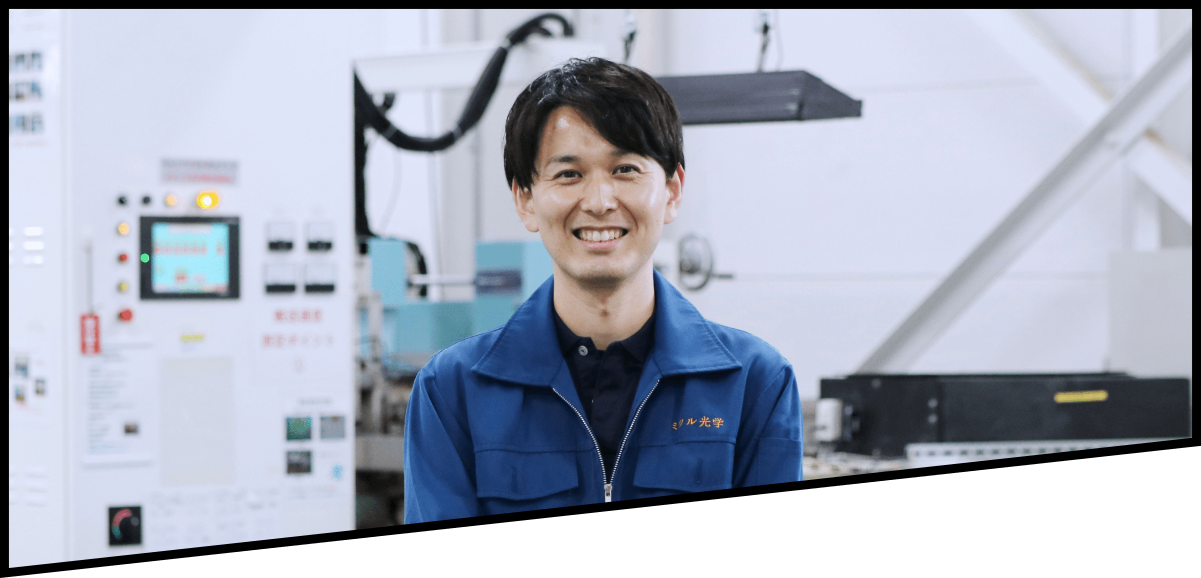 大型設備の前で笑顔を向ける2021年入社の男性社員