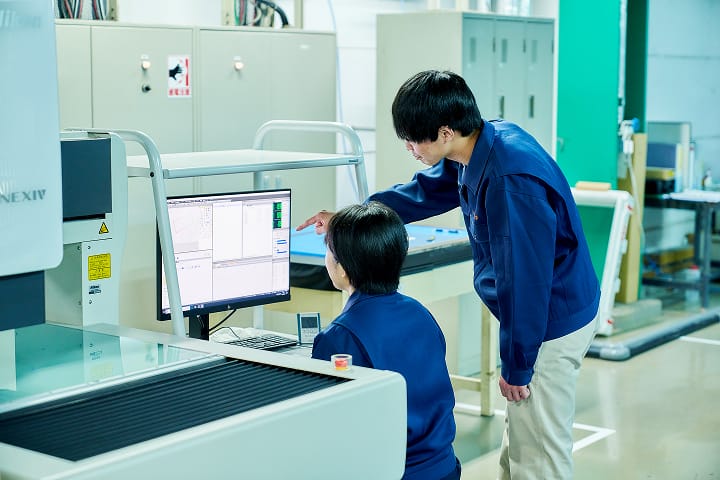 パソコン画面を見ながら新人社員に指導をしている男性社員